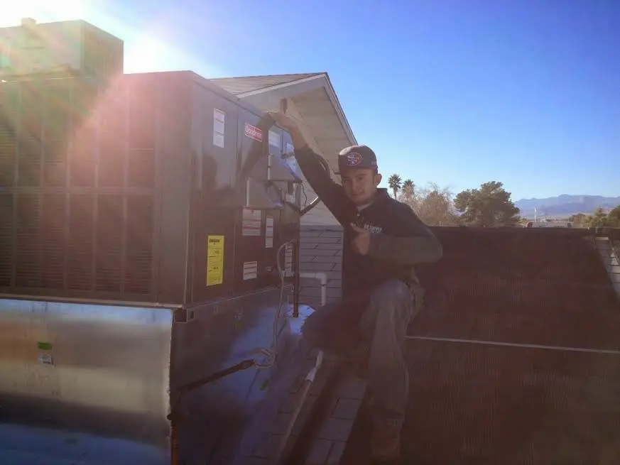 HVAC technician performing AC Tune-Up on a rooftop unit in Corona